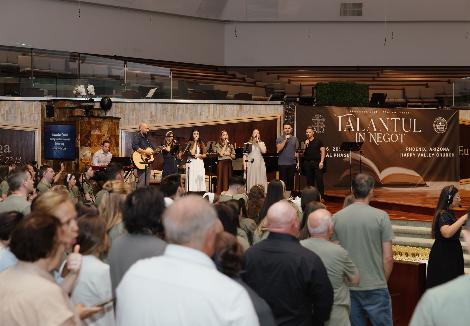 Worship team in front of the Talantul în Negoț national banner